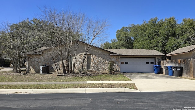 view of front facade with a garage, stone siding, fence, and driveway