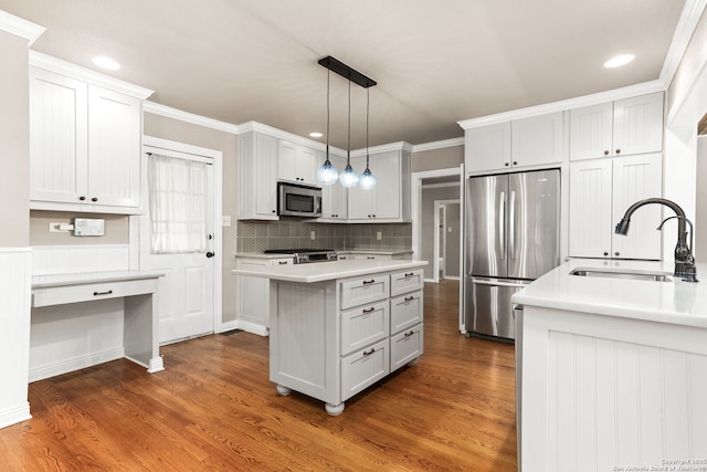 kitchen featuring dark wood finished floors, light countertops, appliances with stainless steel finishes, a sink, and a kitchen island