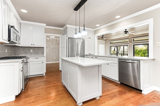 kitchen featuring stainless steel appliances, tasteful backsplash, light countertops, ornamental molding, and a sink