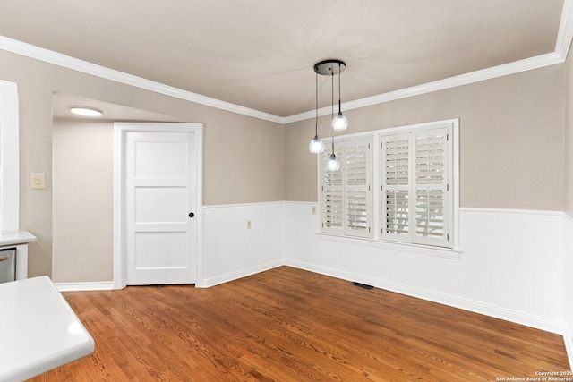 unfurnished dining area featuring wainscoting, crown molding, visible vents, and wood finished floors