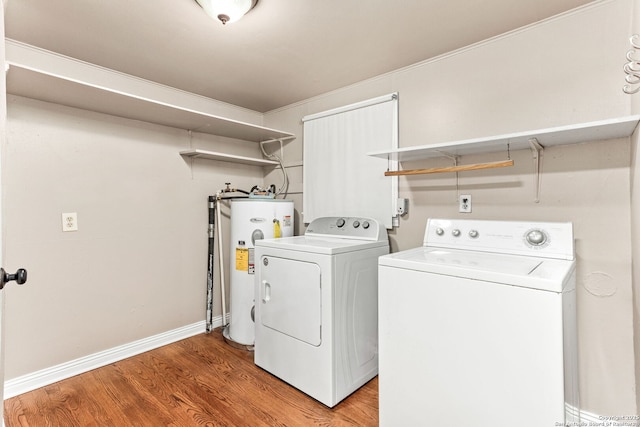 clothes washing area with laundry area, baseboards, light wood-style flooring, washing machine and clothes dryer, and electric water heater