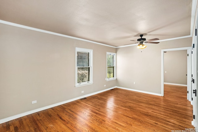 empty room with ornamental molding, ceiling fan, baseboards, and wood finished floors