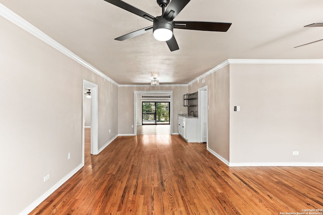 empty room with a ceiling fan, baseboards, ornamental molding, and wood finished floors