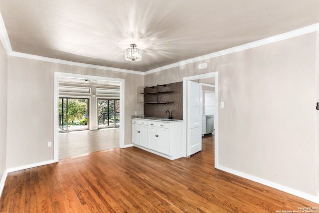 interior space featuring ornamental molding, baseboards, and wood finished floors