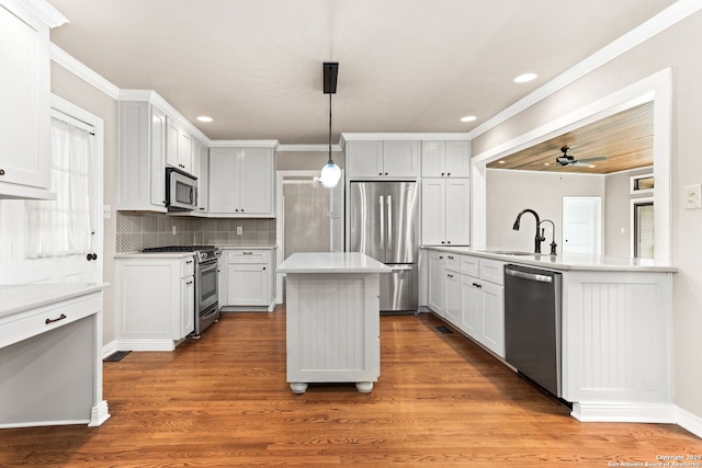 kitchen with stainless steel appliances, wood finished floors, a sink, a center island, and decorative backsplash