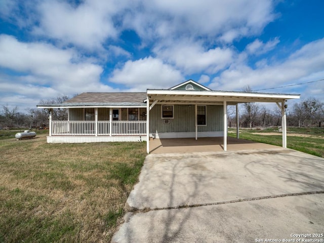 farmhouse-style home featuring concrete driveway, a porch, a carport, and a front yard