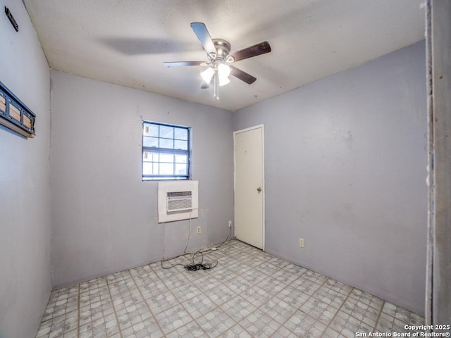 spare room with light floors, a wall unit AC, and a ceiling fan