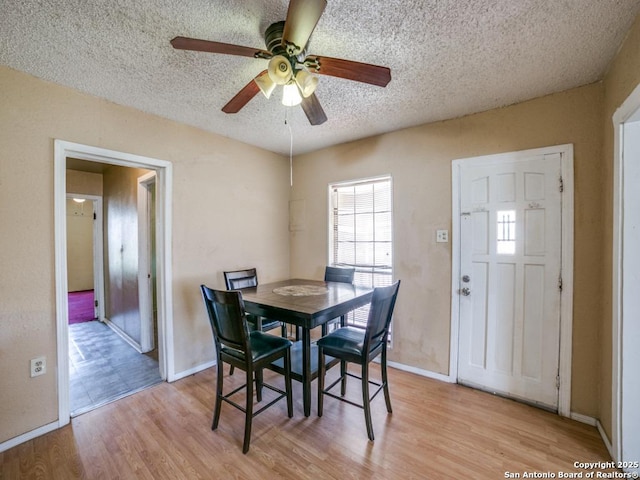 dining room with a ceiling fan, baseboards, a textured ceiling, and light wood finished floors