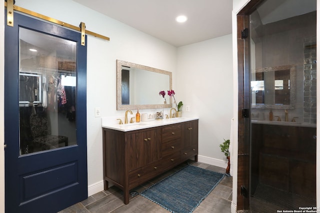 full bath with double vanity, wood finished floors, a sink, and baseboards