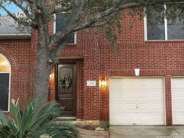 view of exterior entry with a garage and brick siding