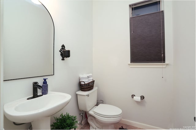 bathroom with a sink, toilet, and baseboards