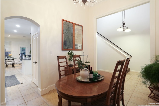 dining space with light tile patterned floors, baseboards, arched walkways, and a chandelier