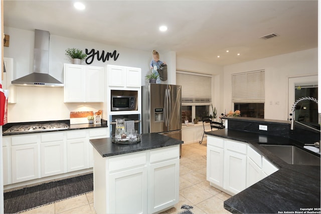 kitchen with visible vents, appliances with stainless steel finishes, white cabinets, a sink, and wall chimney range hood