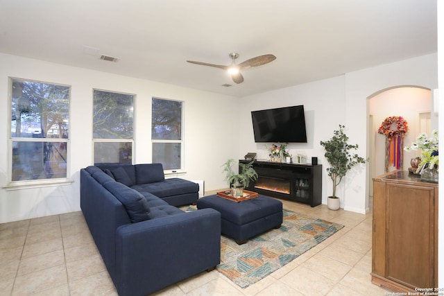 living area featuring ceiling fan, light tile patterned floors, a glass covered fireplace, and visible vents