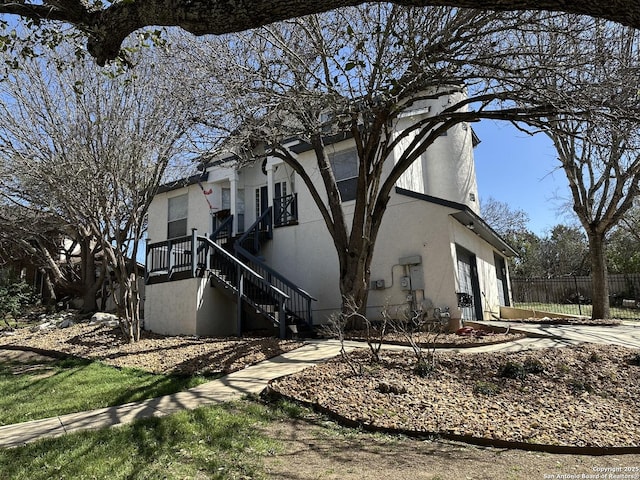 view of home's exterior with driveway, a garage, fence, and stucco siding