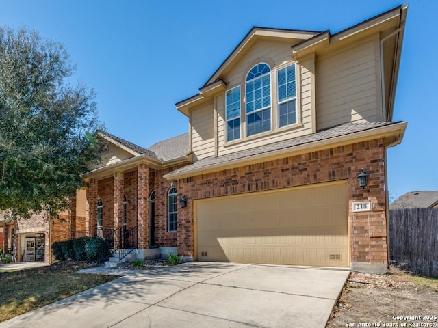 traditional-style home with a garage, brick siding, concrete driveway, and fence