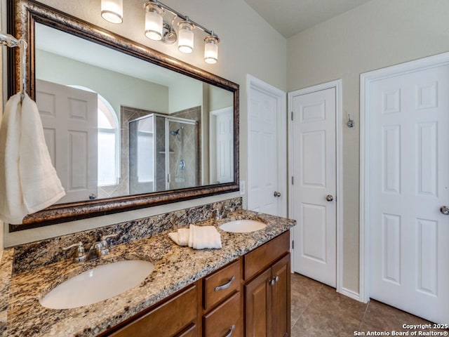 full bathroom featuring double vanity, a shower stall, tile patterned floors, and a sink