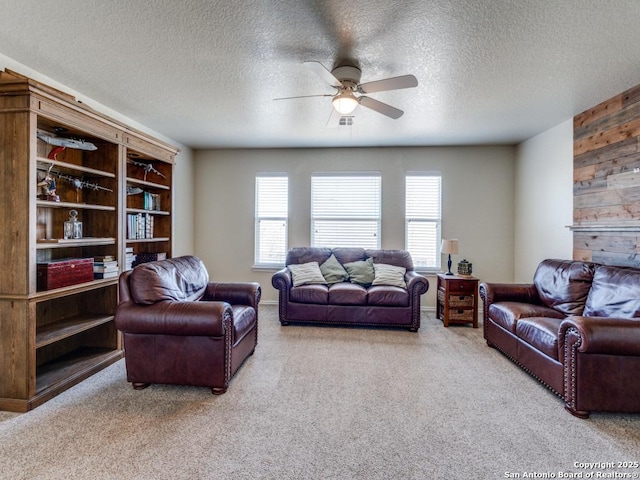 carpeted living room with visible vents, wood walls, a textured ceiling, and a ceiling fan