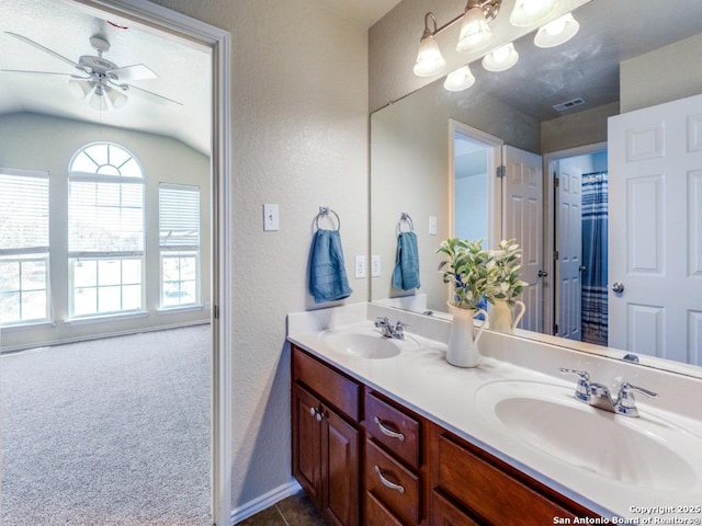 bathroom with double vanity, visible vents, a textured wall, and a sink