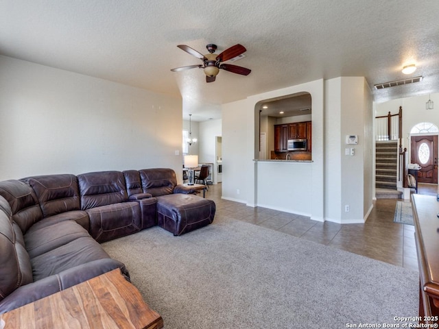 carpeted living room with visible vents, stairway, a ceiling fan, and tile patterned flooring