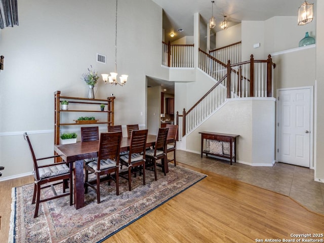 dining area with visible vents, baseboards, stairway, an inviting chandelier, and wood finished floors