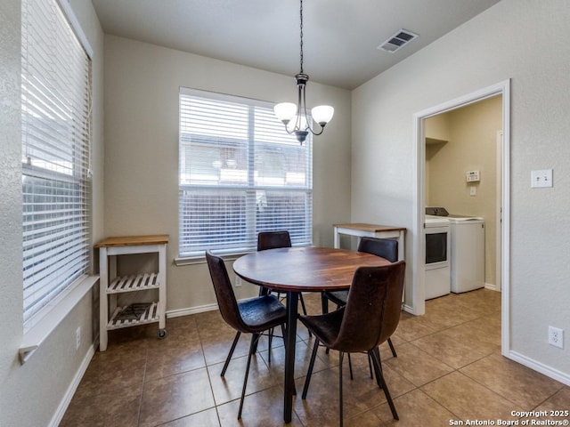 dining area featuring visible vents, baseboards, a chandelier, light tile patterned floors, and washer and dryer