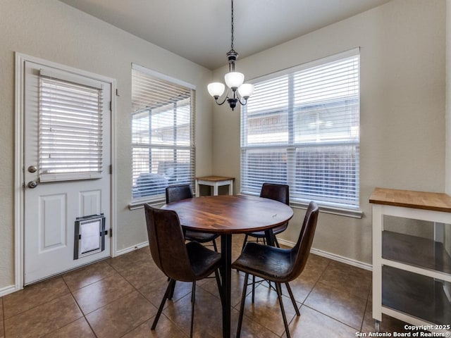 dining area featuring tile patterned flooring, a chandelier, and baseboards