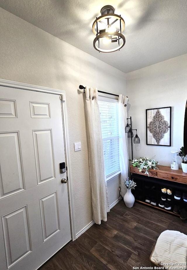 entrance foyer featuring baseboards, dark wood finished floors, and a textured ceiling