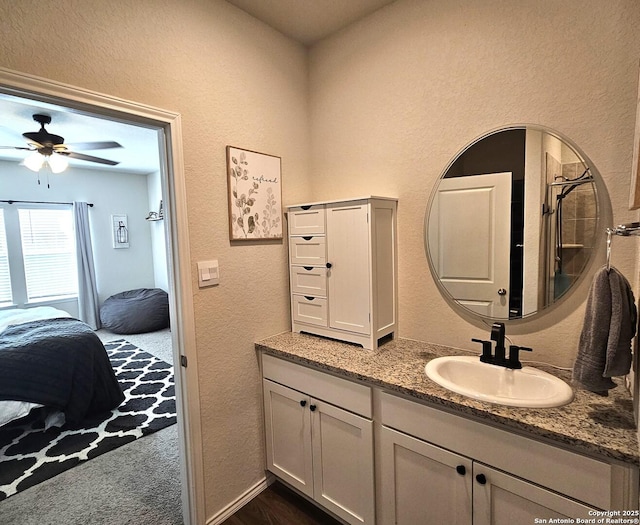 ensuite bathroom featuring a textured wall, ensuite bath, vanity, and a ceiling fan