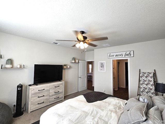 bedroom featuring a ceiling fan, visible vents, dark carpet, and a textured ceiling