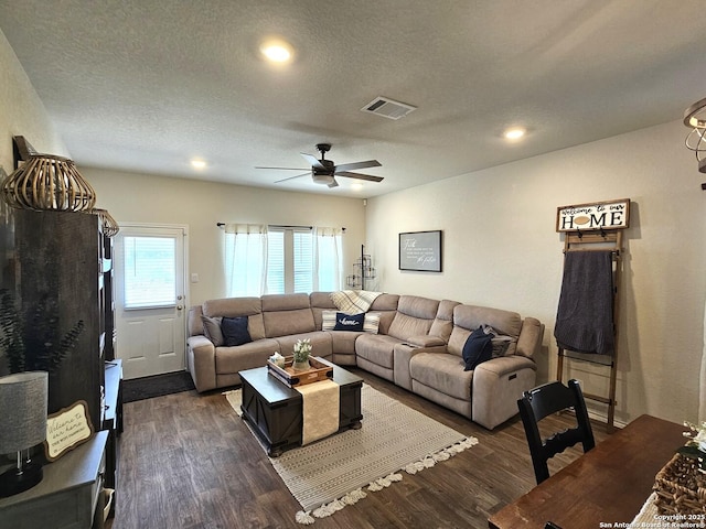 living room featuring a textured ceiling, ceiling fan, dark wood-type flooring, and visible vents