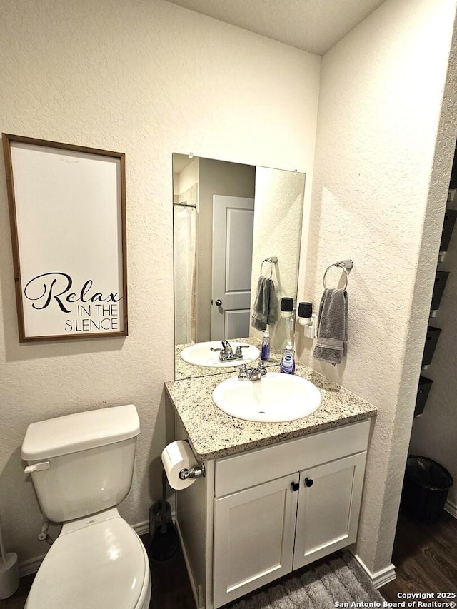 bathroom featuring vanity, an enclosed shower, wood finished floors, and toilet