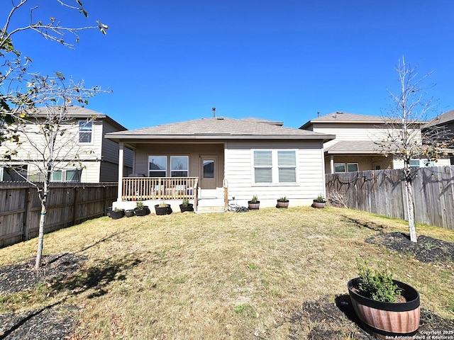 rear view of property with a fenced backyard and a yard