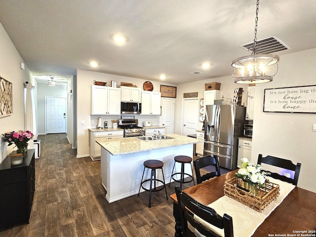 kitchen with visible vents, an island with sink, dark wood-style floors, appliances with stainless steel finishes, and a sink