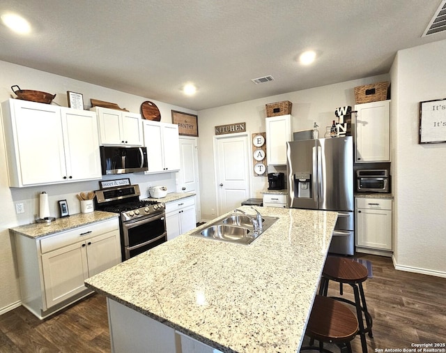 kitchen featuring appliances with stainless steel finishes, a sink, visible vents, and a kitchen breakfast bar