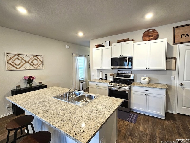 kitchen with stainless steel appliances, white cabinets, a sink, and dark wood-style floors