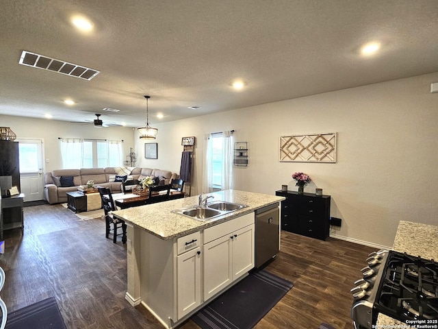 kitchen featuring visible vents, dishwasher, an island with sink, dark wood-style floors, and a sink