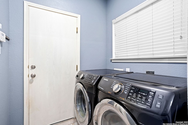 clothes washing area with a textured wall, laundry area, and independent washer and dryer