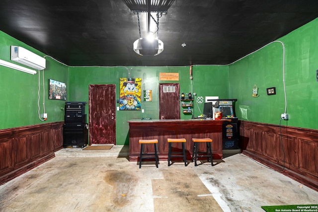 bar with wainscoting, a wall unit AC, unfinished concrete flooring, and a dry bar