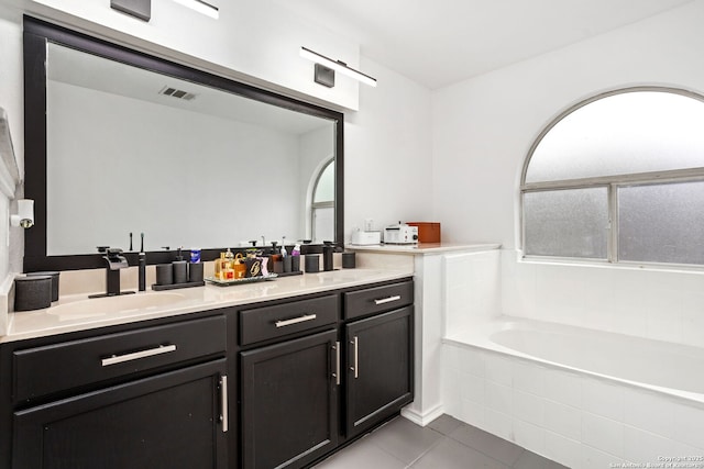 full bathroom with tile patterned flooring, a sink, visible vents, a bath, and double vanity