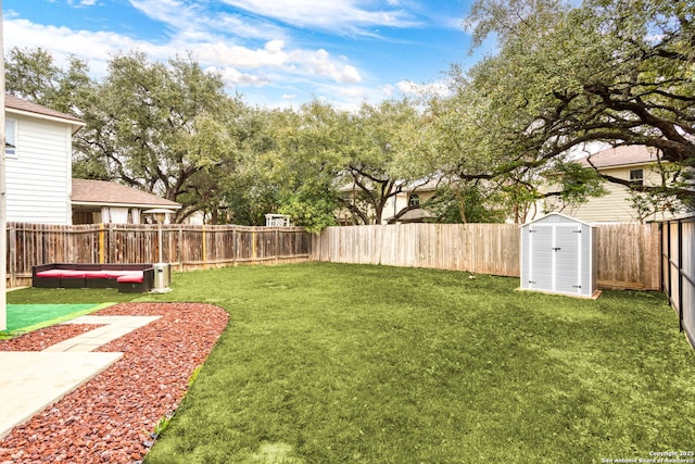 view of yard featuring a fenced backyard, a shed, and an outbuilding