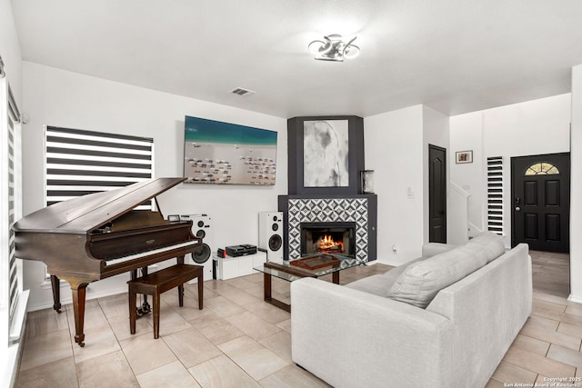 living area with visible vents, stairway, light tile patterned flooring, a tile fireplace, and baseboards