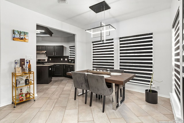 dining space featuring visible vents, a notable chandelier, and baseboards