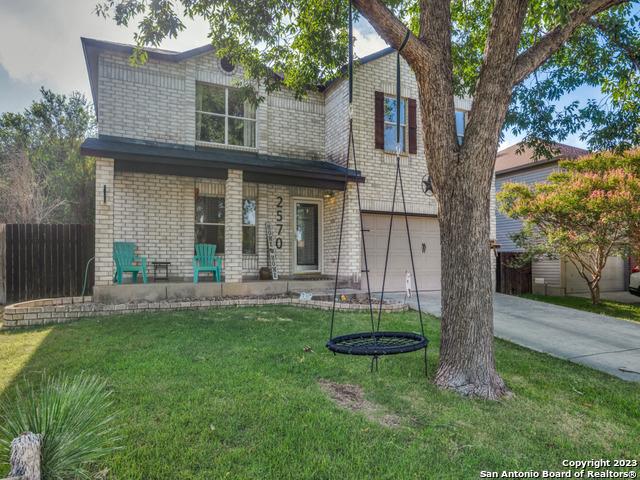 view of front facade with a garage, concrete driveway, brick siding, and fence