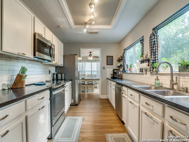 kitchen featuring stainless steel appliances, a sink, visible vents, dark countertops, and a raised ceiling