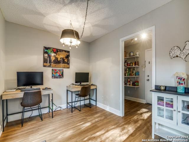 office area with a textured ceiling, baseboards, and wood finished floors