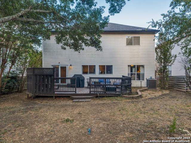 back of property with fence, a wooden deck, and central air condition unit