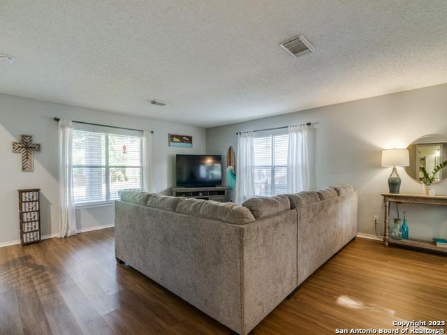 living room with a textured ceiling, wood finished floors, and visible vents