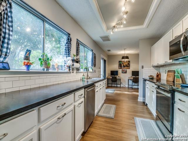 kitchen with dark countertops, a raised ceiling, visible vents, appliances with stainless steel finishes, and a sink