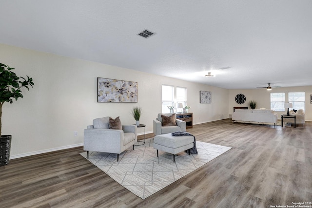 living area with a healthy amount of sunlight, visible vents, baseboards, and wood finished floors